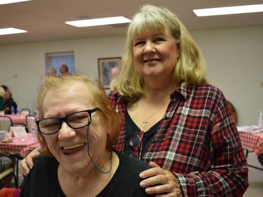 A female advocate stands behind her female partner at our annual Spaghetti Dinner